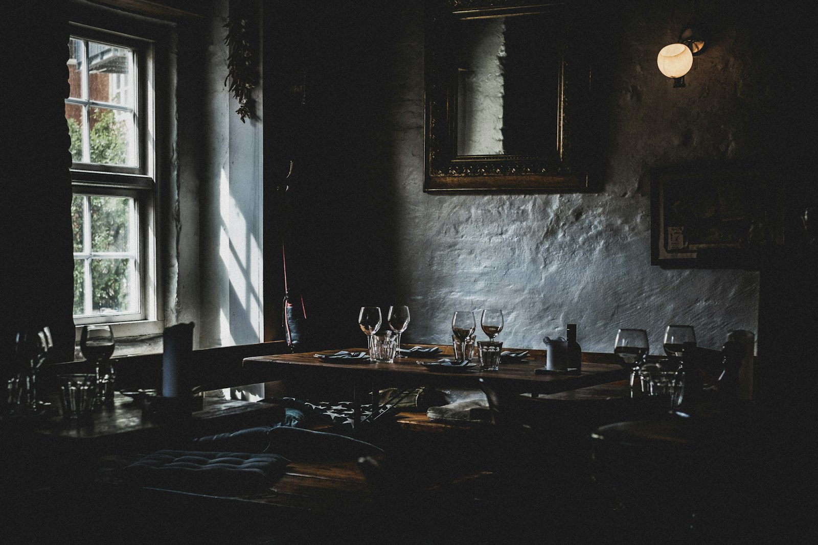 Una sala di ristorante in penombra, con i tavoli apparecchiati